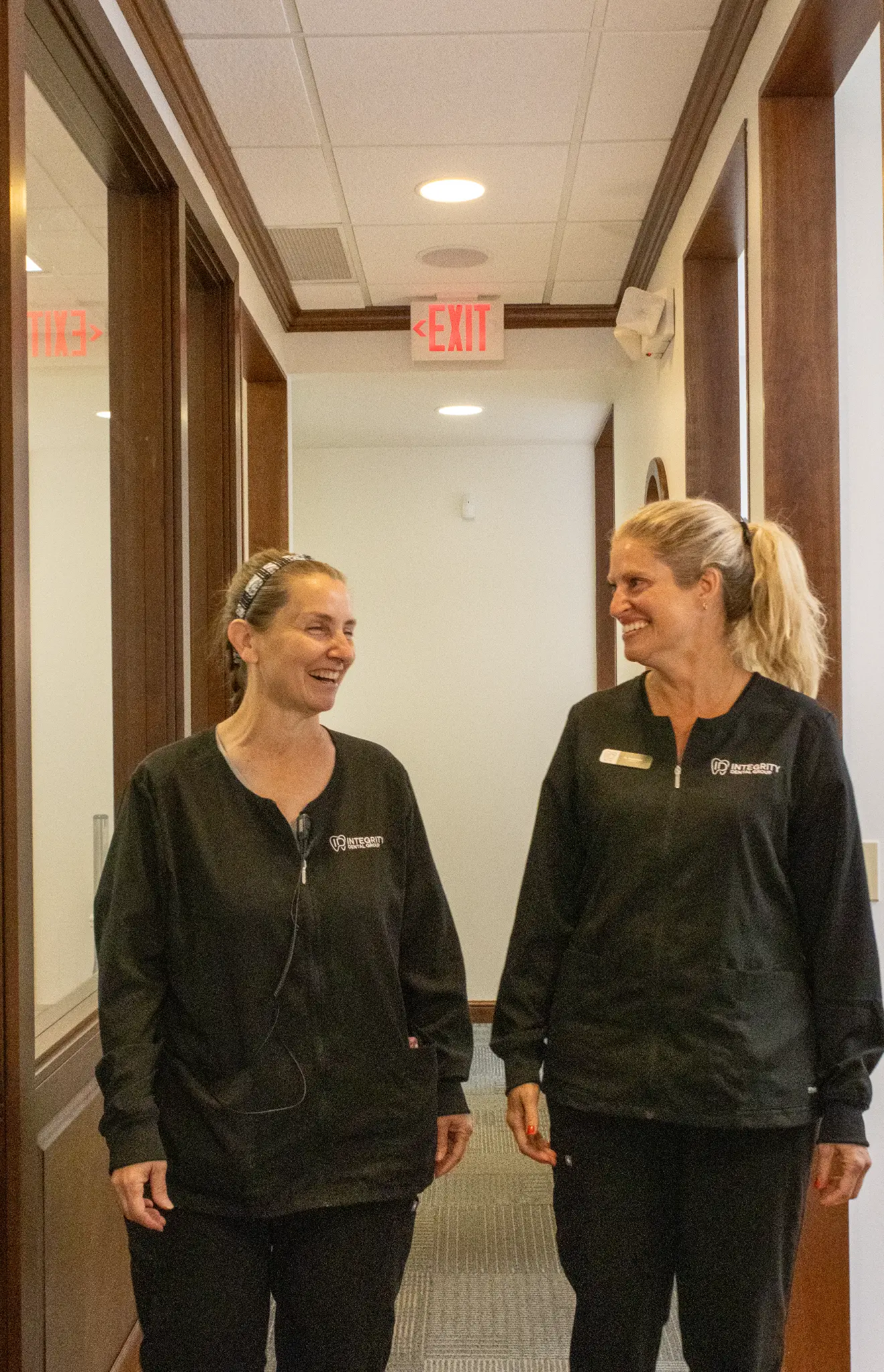 Two Integrity Dental Group team members sharing a laugh while walking through the office hallway